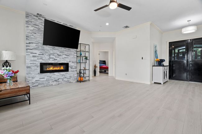 Living room with a ceiling fan, crown molding, wood finished floors, and a fireplace | Image 8