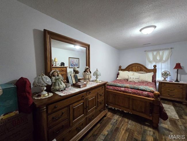 Bedroom with dark wood finished floors and a textured ceiling | Image 13