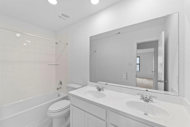 The secondary bath features tile flooring, white cabinetry and light countertops and a shower/tub combo. Perfect for accommodating any visiting family and friends. | Image 20