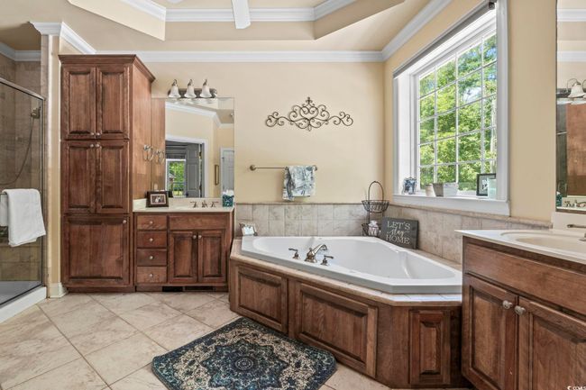 Full bath with ornamental molding, a shower stall, a bath, two vanities, and tile patterned floors | Image 15