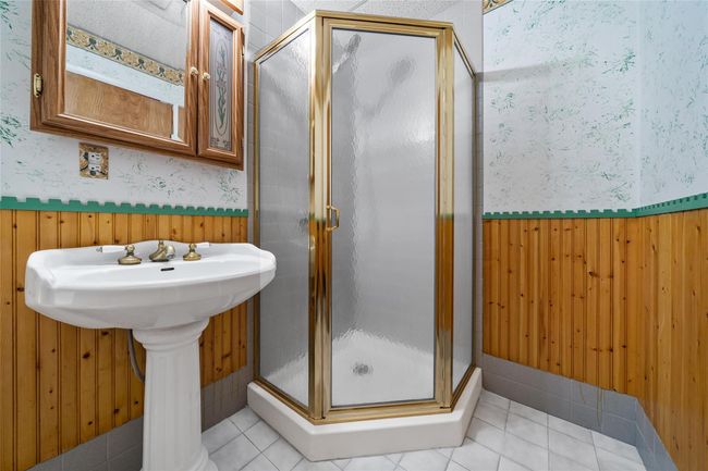 Full bathroom featuring wallpapered walls, a shower stall, a wainscoted wall, tile patterned flooring, and wooden walls | Image 28