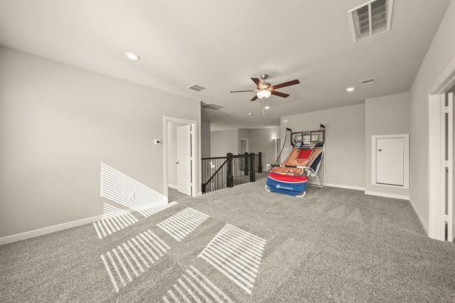 Spacious and sunlit game room with plush carpeting and room for play, media, or a second lounge area. | Image 23