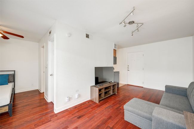 Living room featuring ceiling fan, dark wood finished floors, baseboards, and track lighting | Image 32