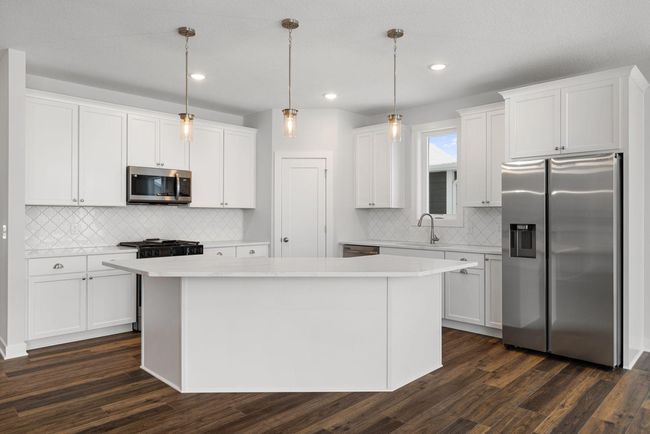 This gorgeous kitchen boasts quality painted maple cabinets, upgraded quartz countertops, a sleek backsplash, a large walk-in pantry, and a MASSIVE center island perfect for entertaining. | Image 15
