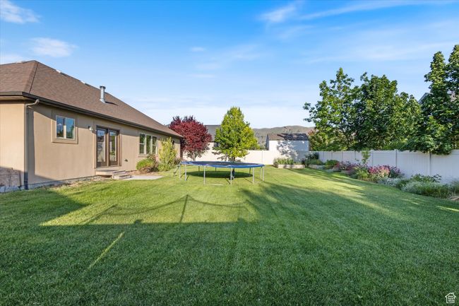 View of yard featuring a trampoline and entry steps | Image 21