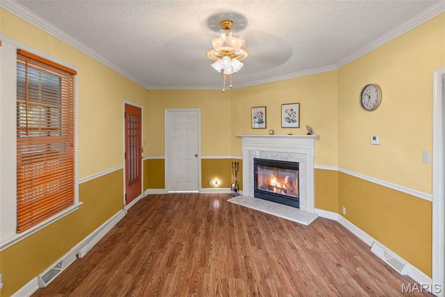 Unfurnished living room with a glass covered fireplace, a ceiling fan, wood finished floors, ornamental molding, and a textured ceiling | Image 15
