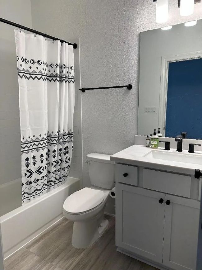 Full bathroom featuring a textured wall, vanity, shower / bath combo with shower curtain, and wood finished floors | Image 10