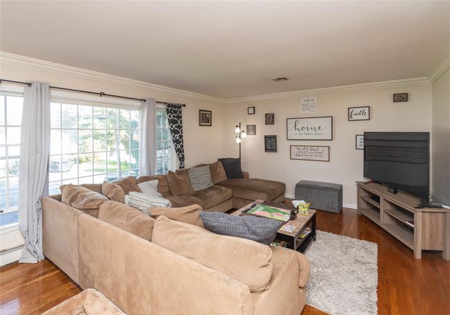 Living room with baseboards, ornamental molding, wood finished floors, and visible vents | Image 4
