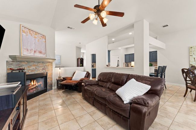 Living area featuring light tile patterned flooring, high vaulted ceiling, a ceiling fan, a fireplace, and recessed lighting | Image 7