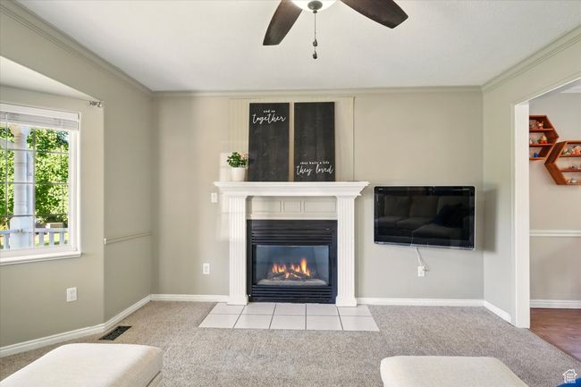 Carpeted living area featuring a fireplace, ceiling fan, ornamental molding, and baseboards | Image 4