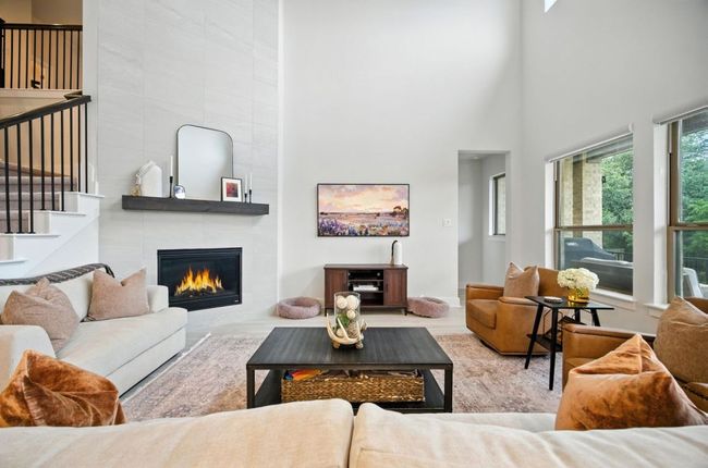 Living room featuring a high ceiling, a fireplace, plenty of natural light, stairs, and wood finished floors | Image 6