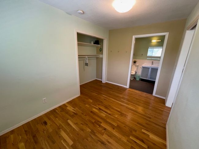 Unfurnished bedroom featuring wood finished floors, a closet, and ensuite bathroom | Image 9