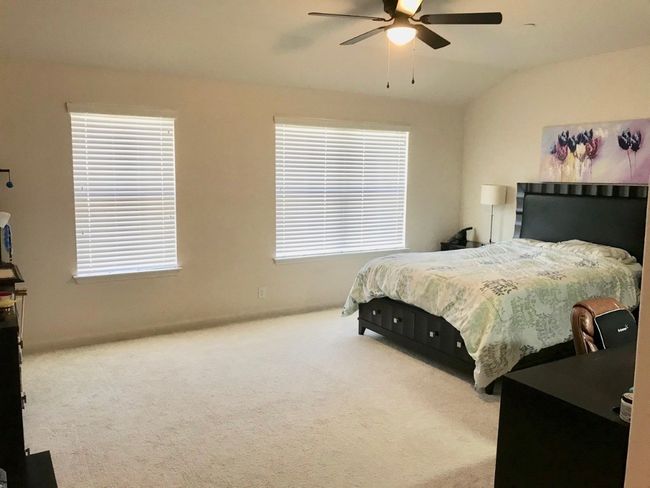 Carpeted bedroom featuring baseboards, ceiling fan, multiple windows, and lofted ceiling | Image 9