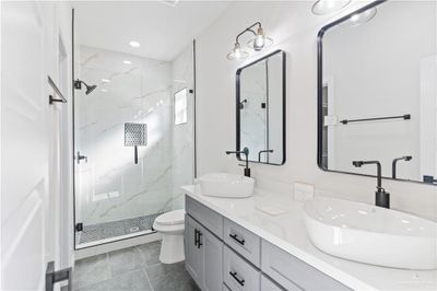 Bathroom with tile patterned flooring, a shower with door, vanity, and toilet | Image 3