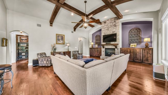 Living room featuring arched walkways, dark wood-style floors, a fireplace, beam ceiling, and recessed lighting | Image 10