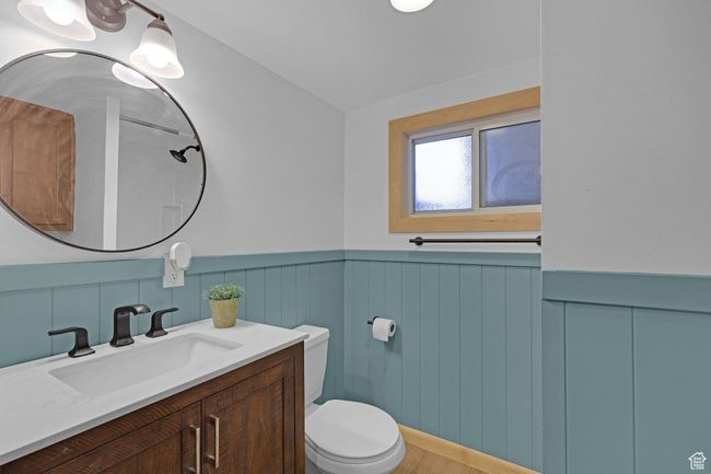 Bathroom featuring toilet, vanity, a wainscoted wall, and wood finished floors | Image 25