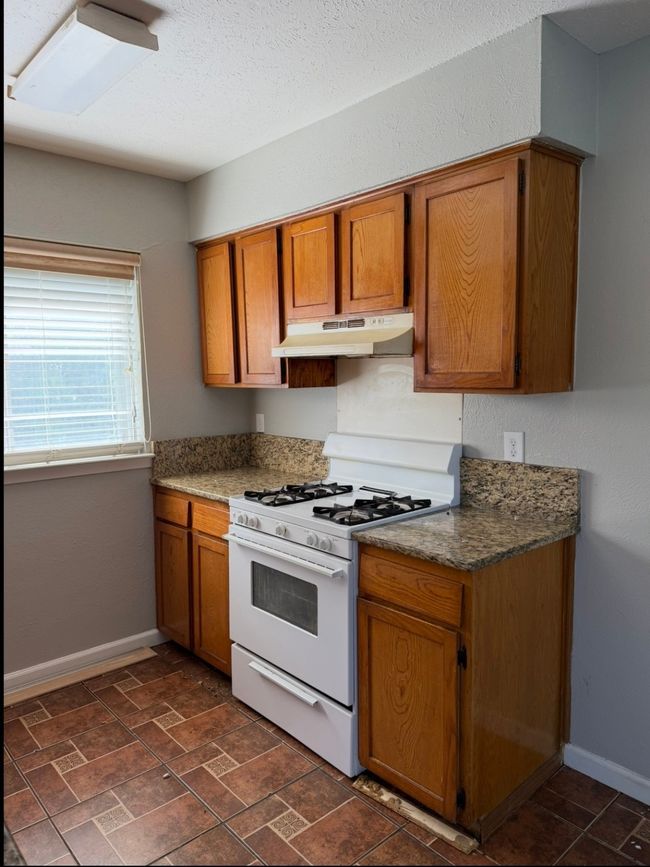 Kitchen featuring white gas range oven, under cabinet range hood, and brown cabinetry | Image 10