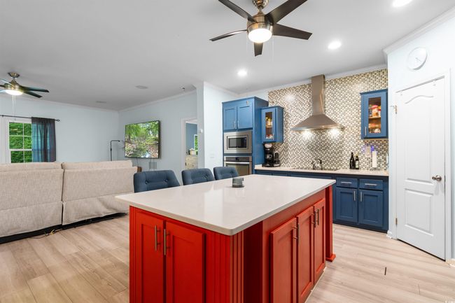 Kitchen with a ceiling fan, wall chimney exhaust hood, stainless steel appliances, plenty of natural light, and ornamental molding | Image 6