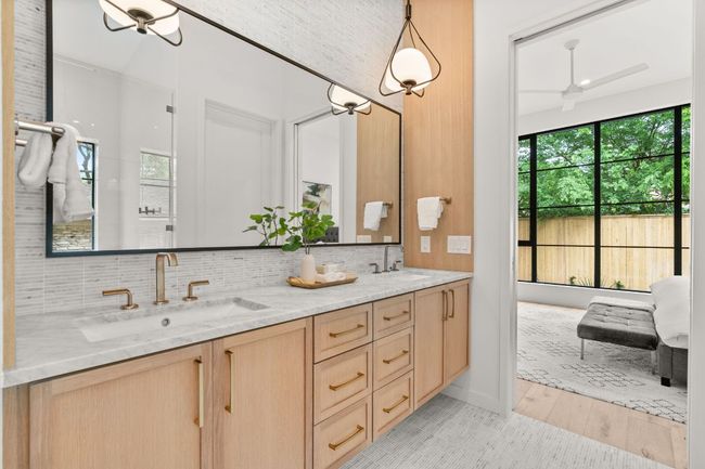 The primary bathroom has a dual vanity, custom lighting, and marble countertops and floors. | Image 16