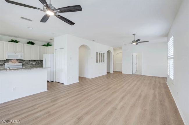 Unfurnished living room featuring open floor concept, with a ceiling fan, arched, and light wood-style floors | Image 6