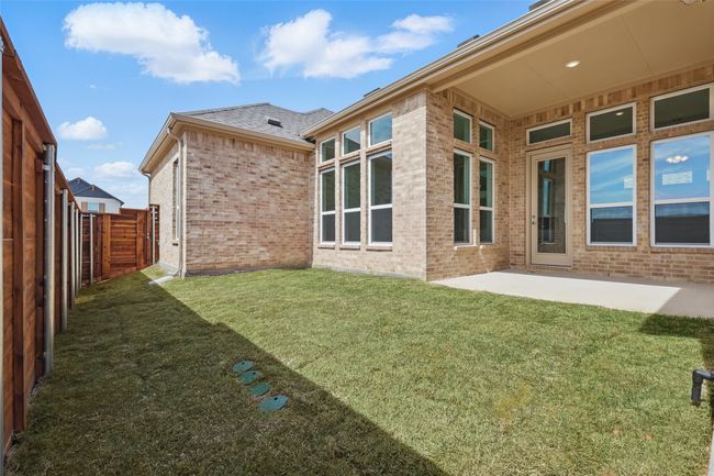 Back of property featuring brick siding, a fenced backyard, a lawn, and a patio | Image 28