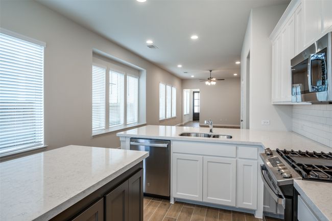 Kitchen featuring white cabinets, sink, light hardwood / wood-style flooring, ceiling fan, and appliances with stainless steel finishes | Image 14