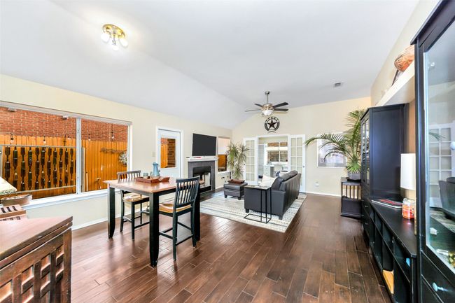 Dining space with a fireplace, ceiling fan, vaulted ceiling, dark wood-style floors, and baseboards | Image 7