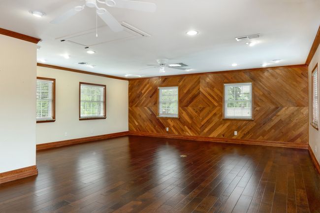Unfurnished room featuring ceiling fan, attic access, crown molding, plenty of natural light, and wooden walls | Image 20
