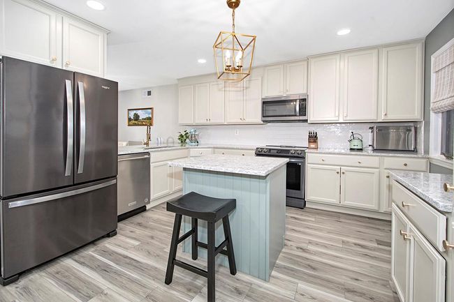 Kitchen featuring decorative backsplash, light wood-style flooring, appliances with stainless steel finishes, an inviting chandelier, and a sink | Image 10