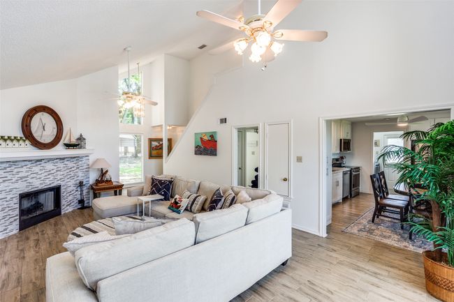 Living room with ceiling fan, high vaulted ceiling, light wood-style floors, and a tile fireplace | Image 6