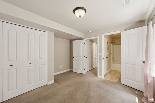 Bedroom with light colored carpet, a closet, and connected bathroom | Image 35