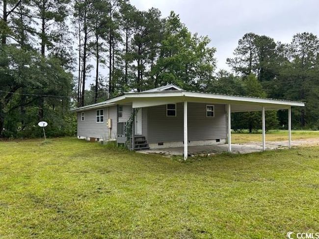 Back of house featuring an attached carport, a lawn, crawl space, and entry steps | Image 4