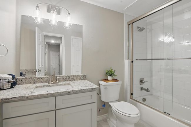 Bathroom featuring vanity, toilet, a notable chandelier, and bath / shower combo with glass door | Image 18