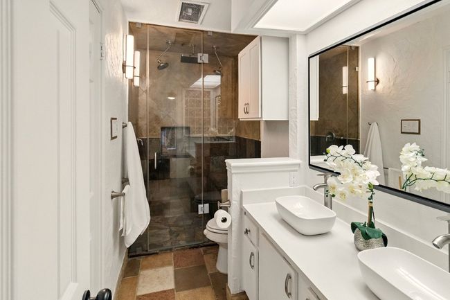 Luxury en-suite bath with glass-enclosed shower featuring dual shower heads plus a rainfall shower head. | Image 15