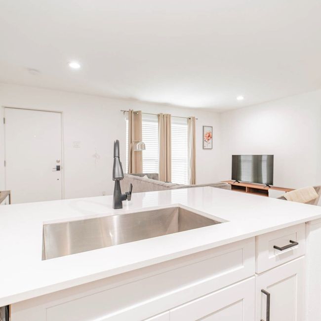Kitchen with light countertops, a sink, recessed lighting, and open floor plan | Image 5