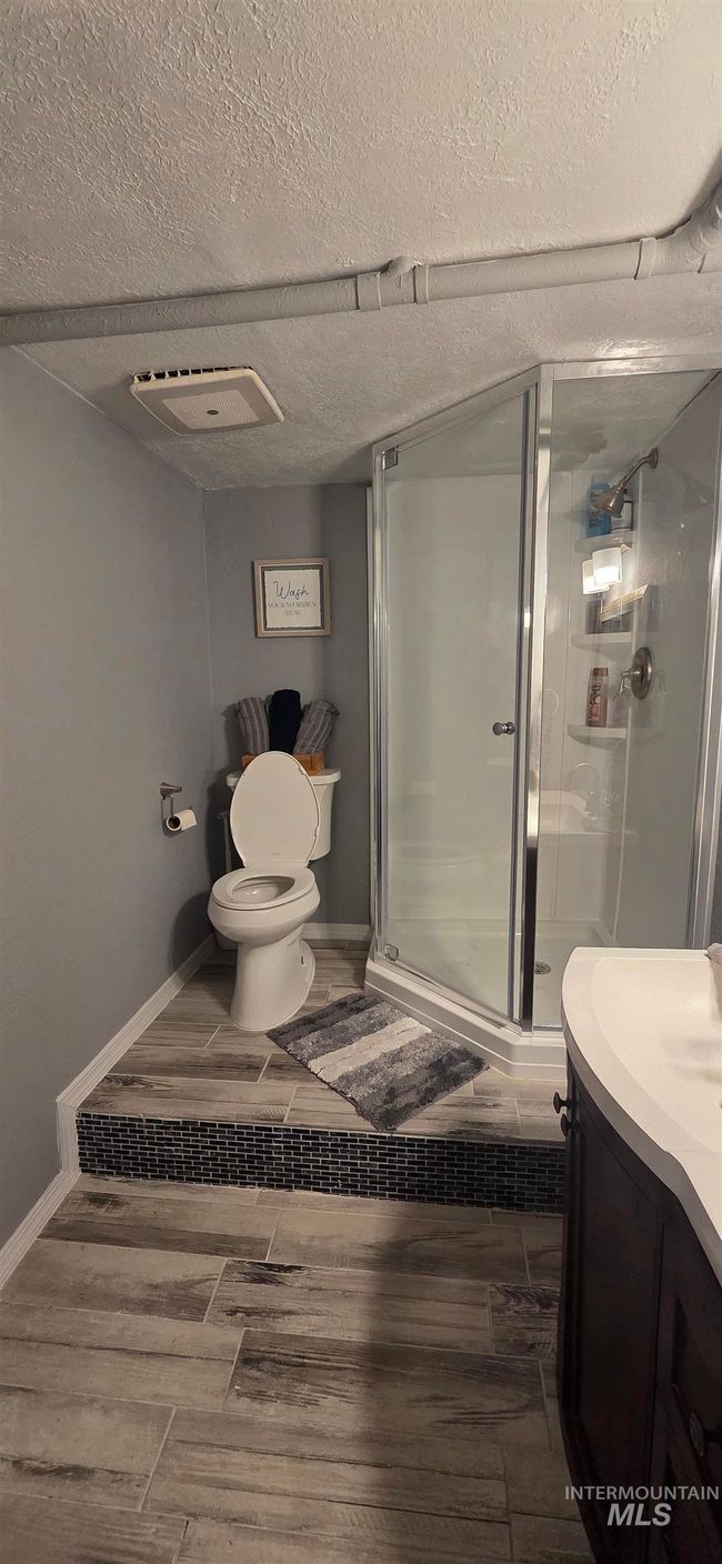 Full bath with vanity, a stall shower, a textured ceiling, and wood finished floors | Image 15