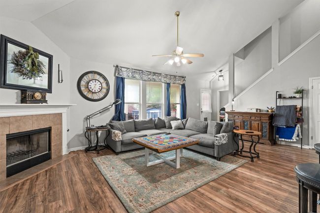 Living room with wood finished floors, lofted ceiling, a fireplace, and ceiling fan | Image 5