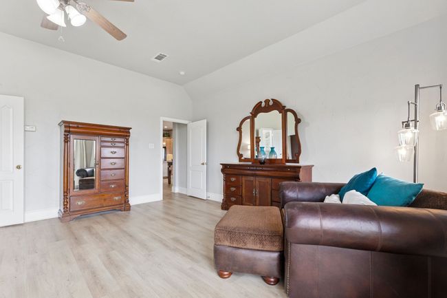 Living area with light wood finished floors, vaulted ceiling, a ceiling fan, and baseboards | Image 20
