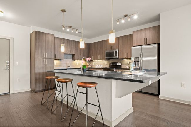 Kitchen featuring stainless steel appliances, rail lighting, dark countertops, and a breakfast bar area | Image 24