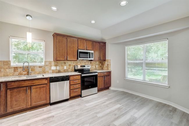 Kitchen featuring appliances with stainless steel finishes, light wood finished floors, healthy amount of natural light, light stone counters, and recessed lighting | Image 11