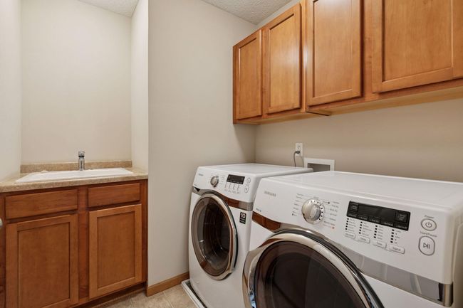 The upper level laundry has cabinets above and a built in utility sink | Image 20