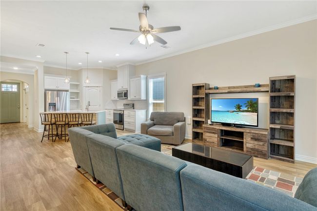 Living room featuring light wood-type flooring, ceiling fan, arched walkways, recessed lighting, and crown molding | Image 14