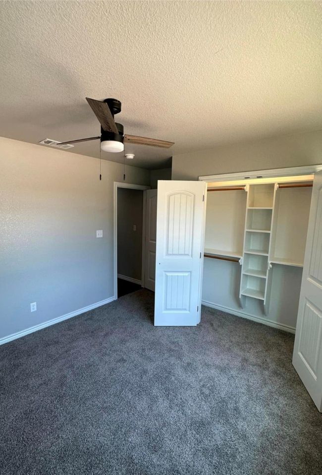 Unfurnished bedroom with a textured ceiling, carpet, a closet, and a ceiling fan | Image 9
