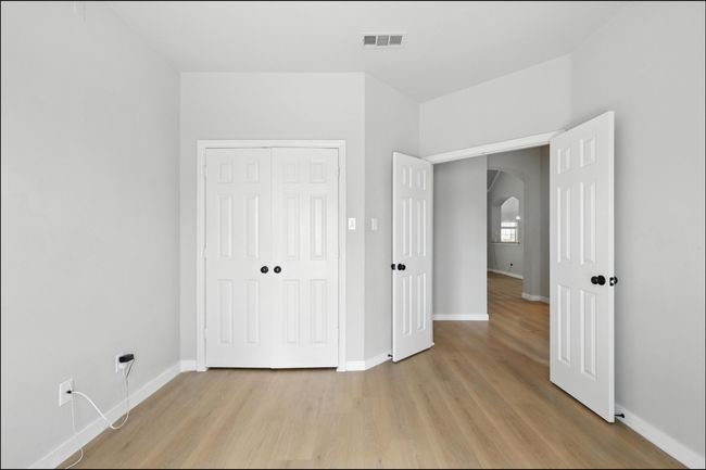 Unfurnished bedroom with arched walkways, light wood-style floors, and a closet | Image 7