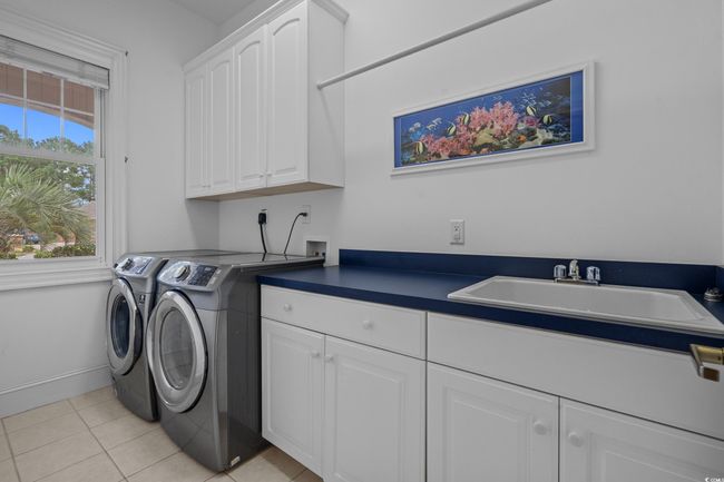 Laundry area featuring cabinet space, separate washer and dryer, and light tile patterned floors | Image 37