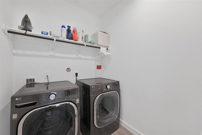 This photo showcases a modern laundry room featuring a matching LG washer and dryer. The space includes a shelf above for storage of laundry essentials, with a clean and minimalistic design. | Image 21