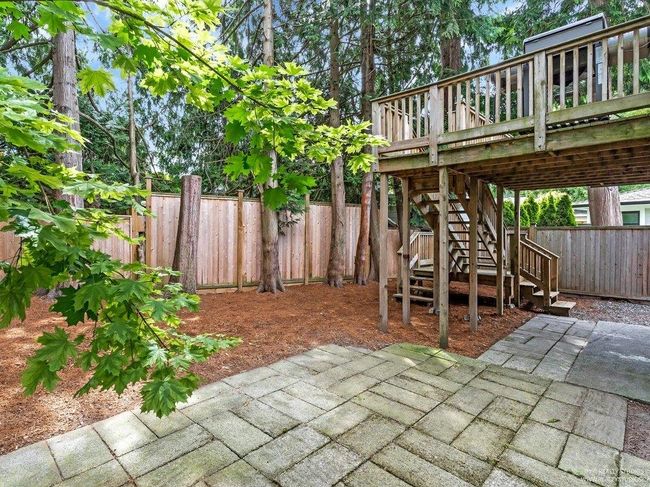 Inviting fenced backyard featuring a patio area, perfect for outdoor dining or a trampoline etc... a wooden deck and stairs to the solarium and kitchen. Hidden and recessed under the solarium and deck is an outdoor workshop and phenomenal storage area. | Image 39