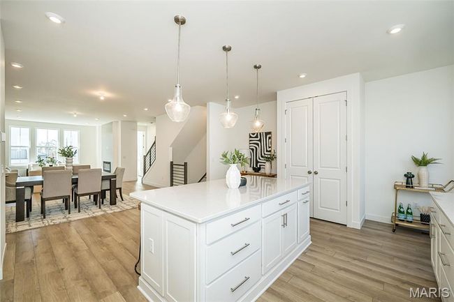 Kitchen with light wood-type flooring, white cabinets, a center island, recessed lighting, and light countertops | Image 9