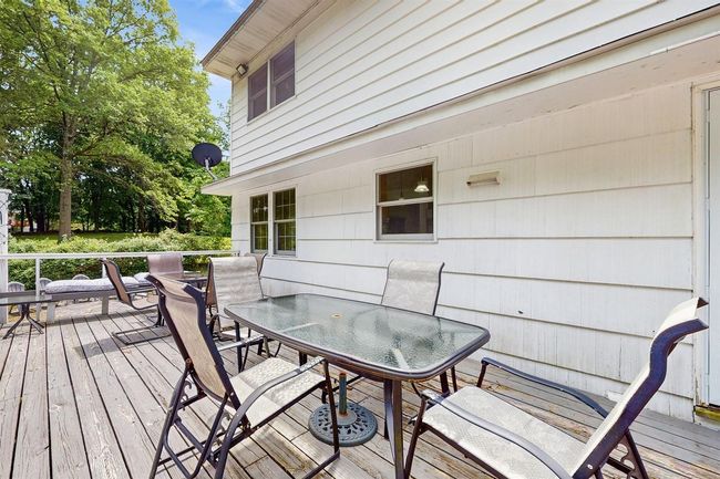 Huge, outdoor dining area on the wooden deck overlooking the wooded area in the back of the property. | Image 42