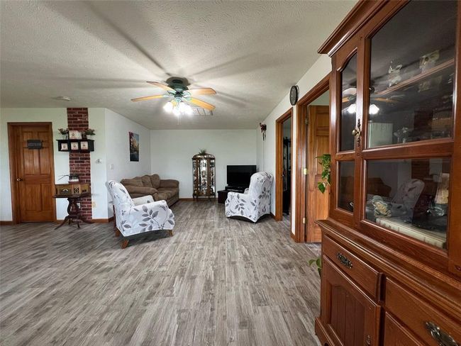 Living room featuring light wood-type flooring, ceiling fan, a textured ceiling, and baseboards | Image 6